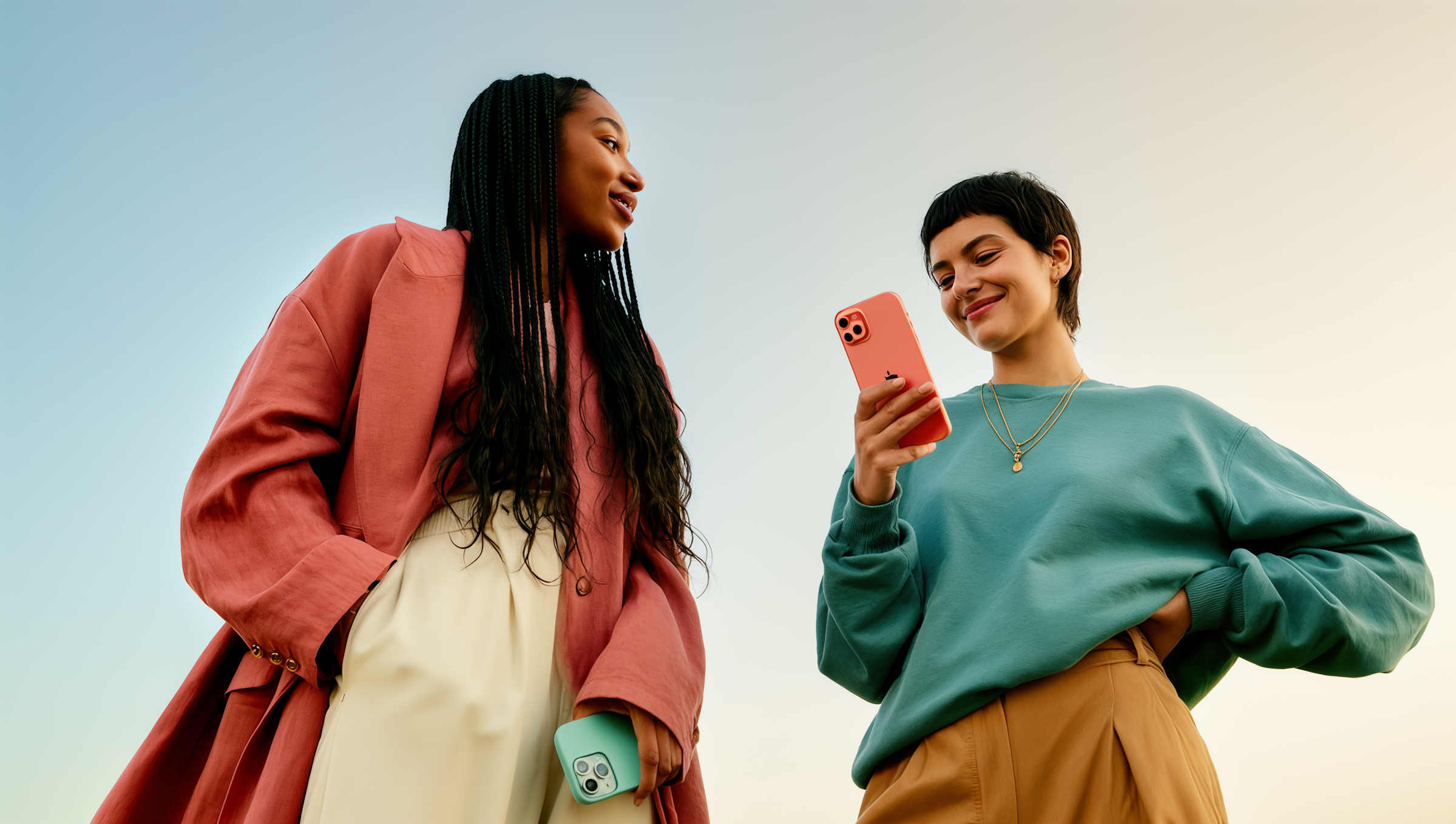 Two models in colorful outfits sharing a phone